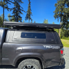Toyota Tacoma 2016–2023 truck canopy mounted on bed with sleek black finish, ideal for secure storage and overlanding adventures