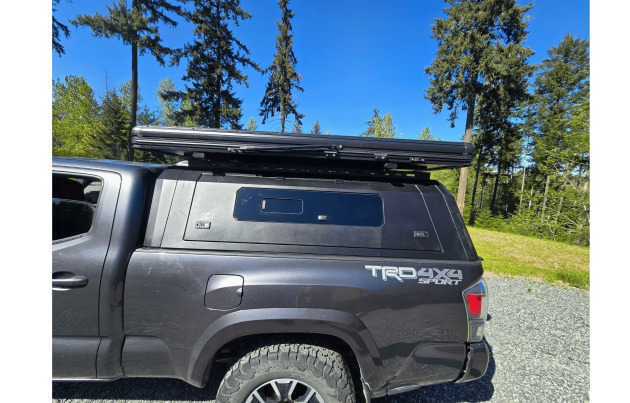 Toyota Tacoma 2016–2023 truck canopy mounted on bed with sleek black finish, ideal for secure storage and overlanding adventures