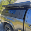 Toyota Tacoma 2016–2023 truck canopy mounted on bed with sleek black finish, ideal for secure storage and overlanding adventures