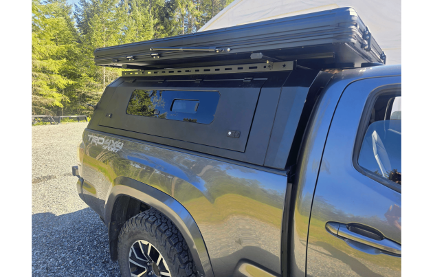 Toyota Tacoma 2016–2023 truck canopy mounted on bed with sleek black finish, ideal for secure storage and overlanding adventures